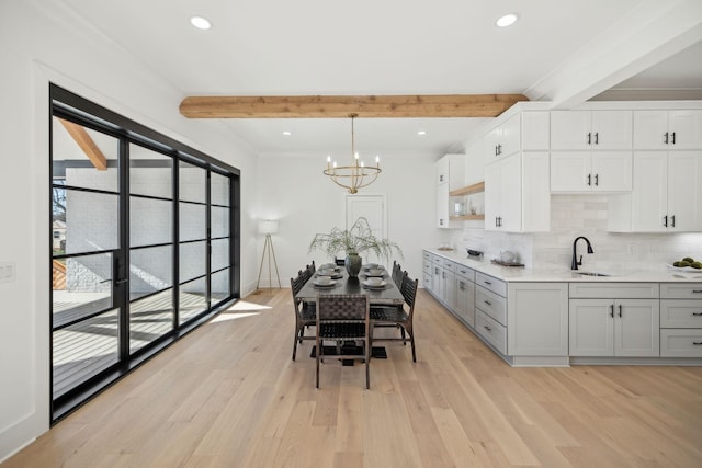 kitchen with white cabinetry, beam ceiling, light hardwood / wood-style flooring, and decorative light fixtures