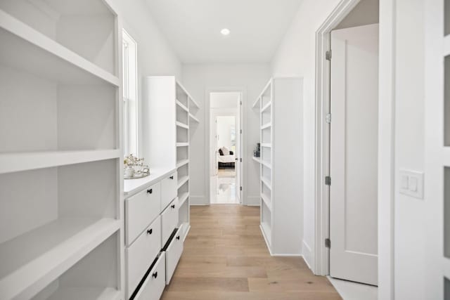 walk in closet with light hardwood / wood-style floors