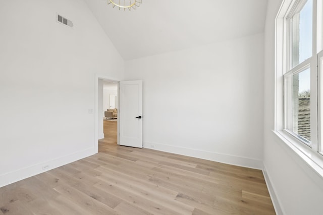 spare room with high vaulted ceiling and light wood-type flooring