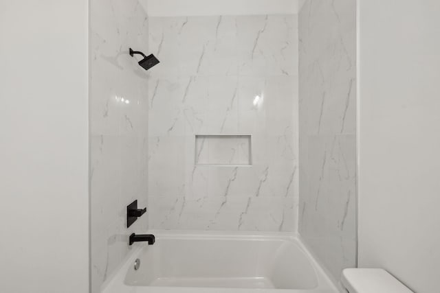 bathroom featuring tiled shower / bath combo and toilet