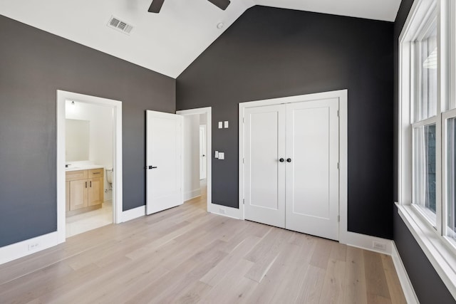 unfurnished bedroom featuring connected bathroom, high vaulted ceiling, a closet, ceiling fan, and light hardwood / wood-style floors