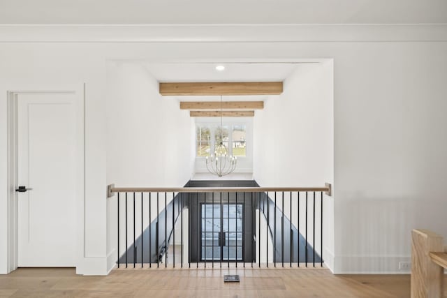 hallway featuring beamed ceiling, wood-type flooring, and an inviting chandelier