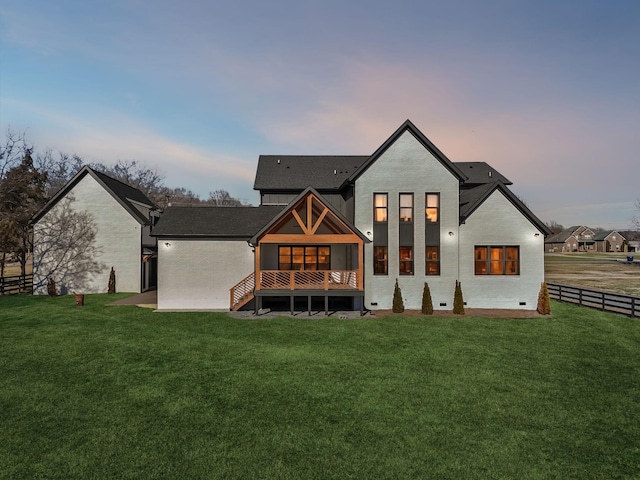 back house at dusk featuring a lawn