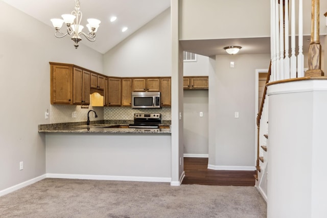 2016 Shamrock Dr, Spring Hill, TN 37174 - kitchen featuring dark carpet, brown cabinetry, appliances with stainless steel finishes, backsplash, and dark stone countertops