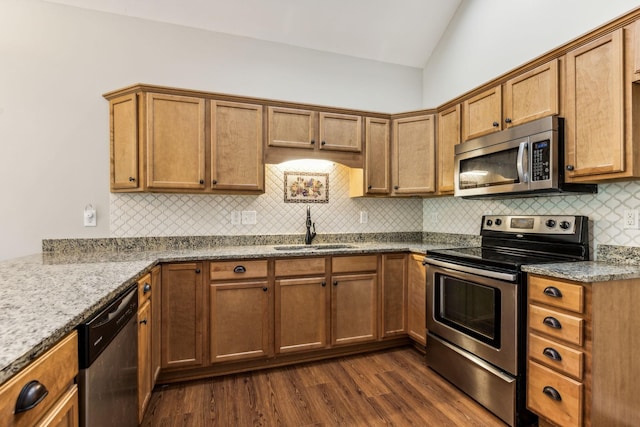 2016 Shamrock Dr, Spring Hill, TN 37174 - kitchen featuring stainless steel appliances, vaulted ceiling, dark wood finished floors, tasteful backsplash, and brown cabinetry