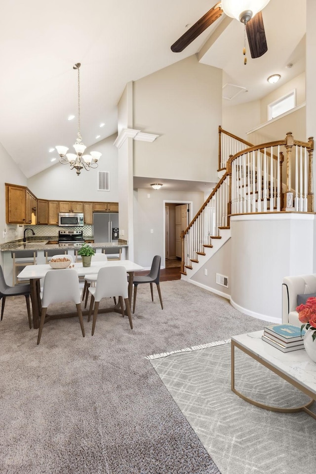 2016 Shamrock Dr, Spring Hill, TN 37174 - dining room with high vaulted ceiling, a chandelier, ceiling fan, stairway, and light colored carpet