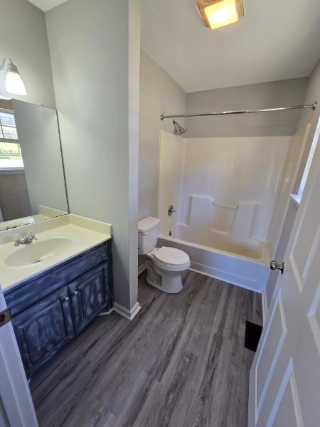 full bathroom with hardwood / wood-style flooring, vanity,  shower combination, and toilet