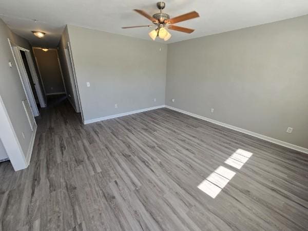 empty room with ceiling fan and dark wood-type flooring