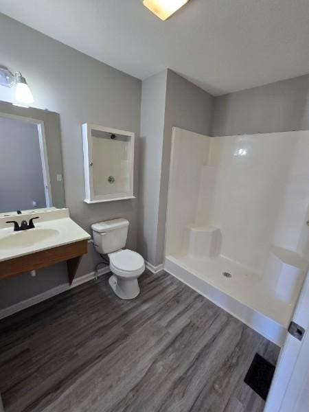 bathroom featuring hardwood / wood-style floors, vanity, toilet, and a shower