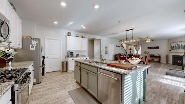 kitchen featuring white cabinetry, stainless steel appliances, a kitchen island with sink, pendant lighting, and sink