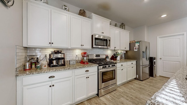 kitchen with light stone counters, white cabinetry, stainless steel appliances, and tasteful backsplash