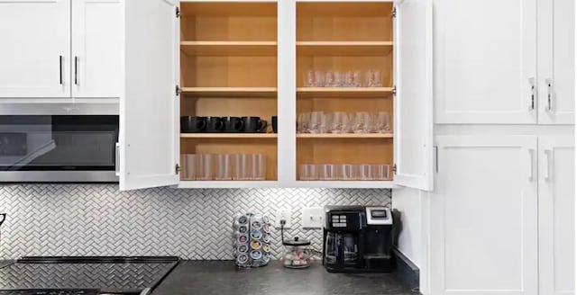 interior space featuring dark countertops, stainless steel microwave, white cabinets, and open shelves