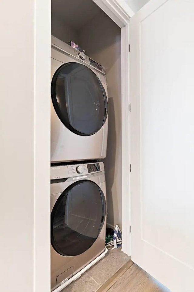 laundry area featuring laundry area, wood finished floors, and stacked washer and dryer