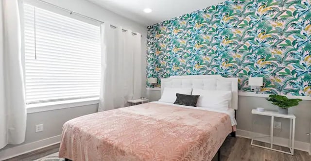 bedroom featuring baseboards, wood finished floors, and wallpapered walls