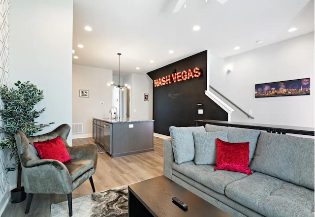 living room featuring light wood finished floors, visible vents, baseboards, recessed lighting, and an inviting chandelier