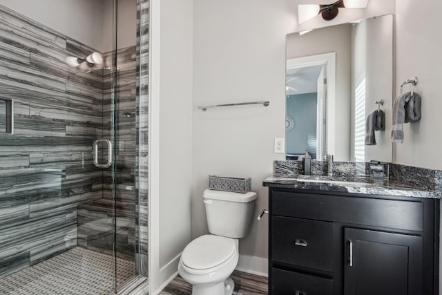 full bath with baseboards, toilet, a stall shower, and vanity