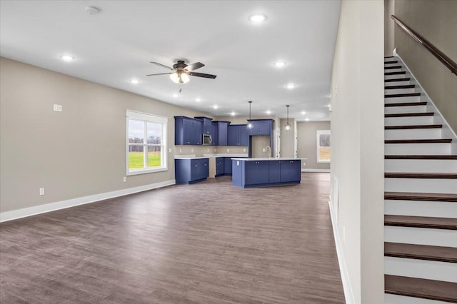 kitchen featuring blue cabinets, ceiling fan, dark wood-type flooring, decorative light fixtures, and a center island