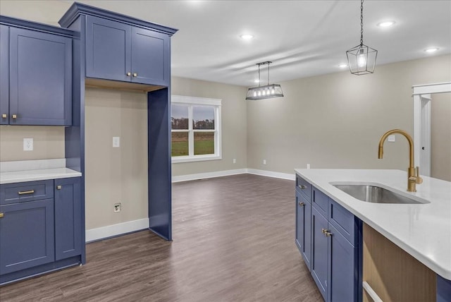 kitchen with blue cabinetry, decorative light fixtures, sink, and dark wood-type flooring