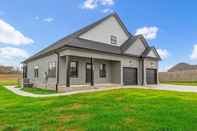 view of front of home featuring a porch, central AC unit, a front yard, and a garage