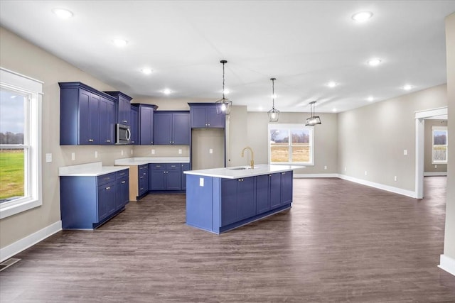 kitchen featuring a wealth of natural light, sink, hanging light fixtures, dark hardwood / wood-style floors, and an island with sink