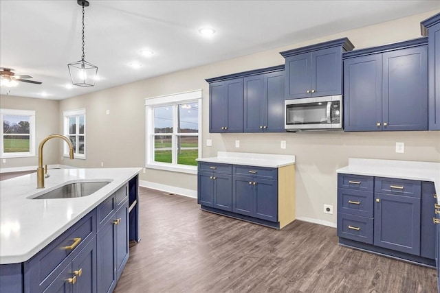 kitchen with blue cabinetry, ceiling fan, sink, and hanging light fixtures