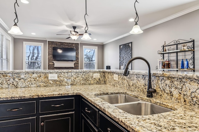 kitchen featuring light stone counters, sink, ceiling fan, and ornamental molding