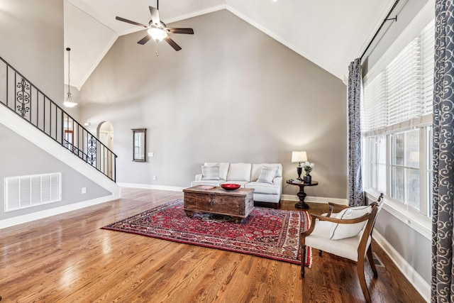 living room featuring hardwood / wood-style floors, plenty of natural light, crown molding, and high vaulted ceiling