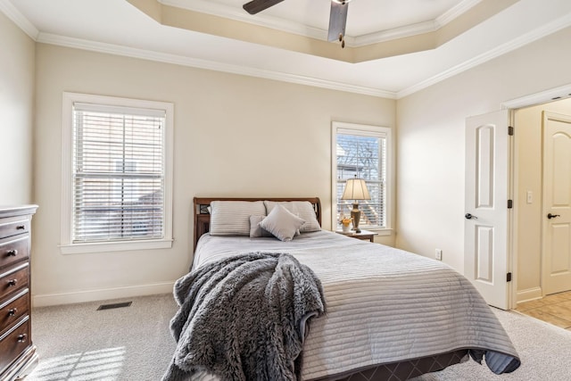 bedroom featuring multiple windows, a tray ceiling, ceiling fan, and light colored carpet