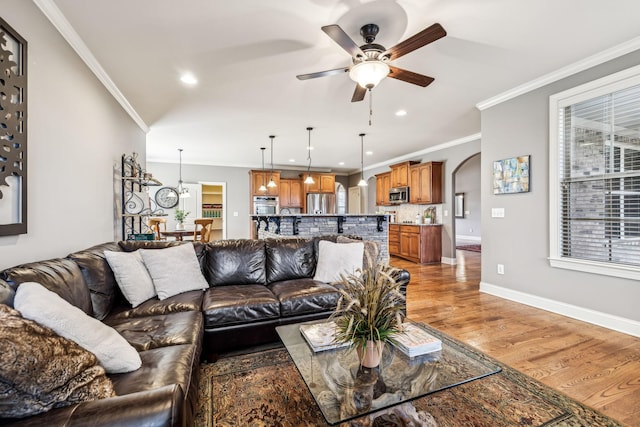 living room featuring hardwood / wood-style flooring, ceiling fan, and crown molding