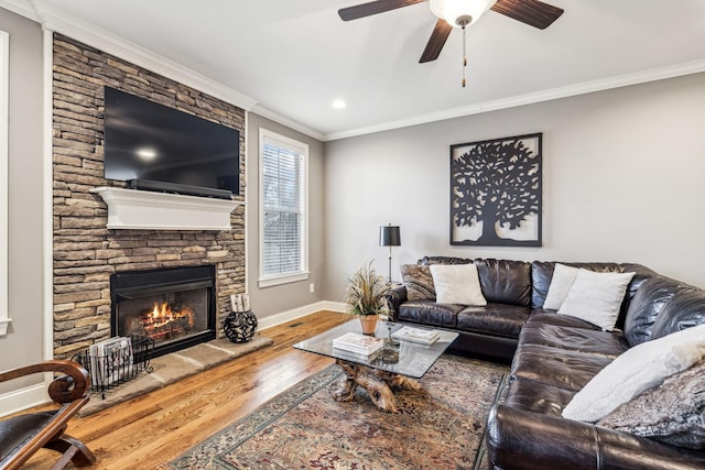 living room featuring hardwood / wood-style flooring, a stone fireplace, ceiling fan, and ornamental molding