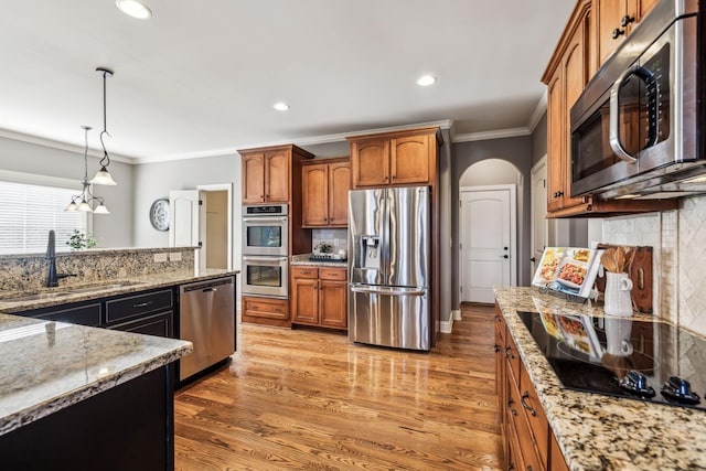 kitchen featuring backsplash, pendant lighting, light stone counters, and stainless steel appliances