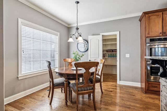 dining area with a chandelier, dark hardwood / wood-style flooring, a healthy amount of sunlight, and ornamental molding