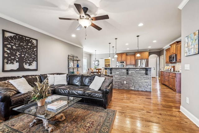 living room with ceiling fan, crown molding, and light hardwood / wood-style flooring