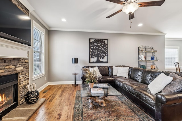 living room featuring a healthy amount of sunlight, wood-type flooring, ornamental molding, and a fireplace