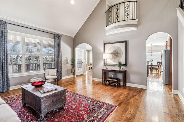 living room featuring hardwood / wood-style floors, high vaulted ceiling, ornamental molding, and a notable chandelier