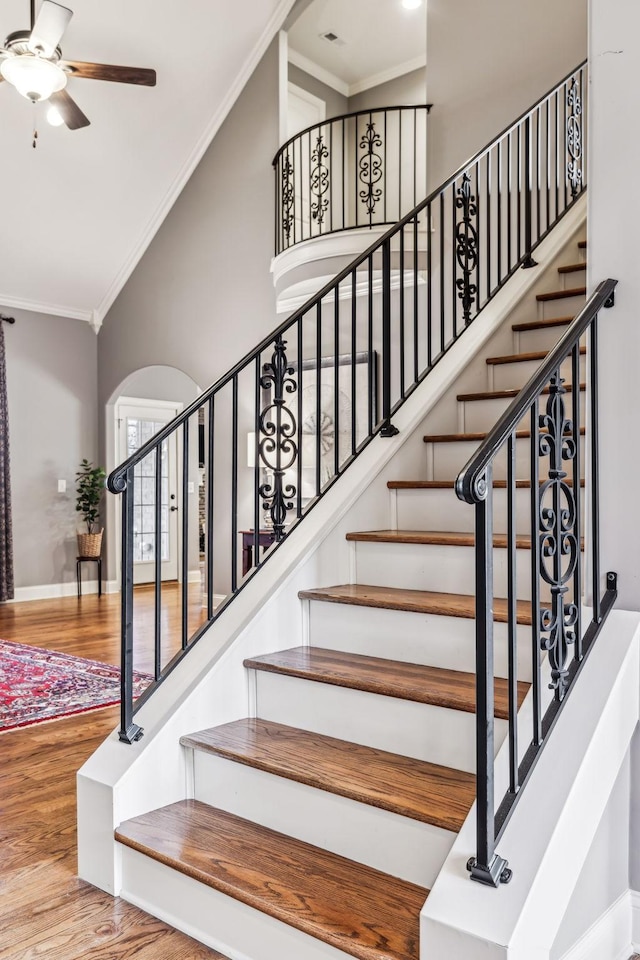 staircase featuring ceiling fan, wood-type flooring, and ornamental molding