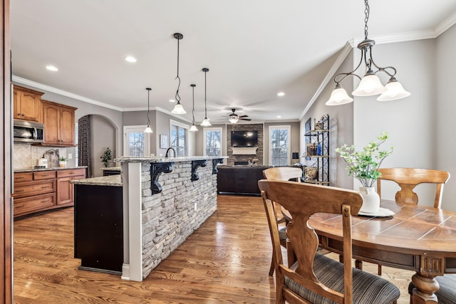 kitchen with dark wood-type flooring, decorative light fixtures, decorative backsplash, ceiling fan with notable chandelier, and ornamental molding