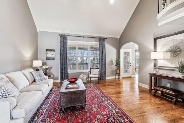 living room featuring hardwood / wood-style flooring, crown molding, and high vaulted ceiling