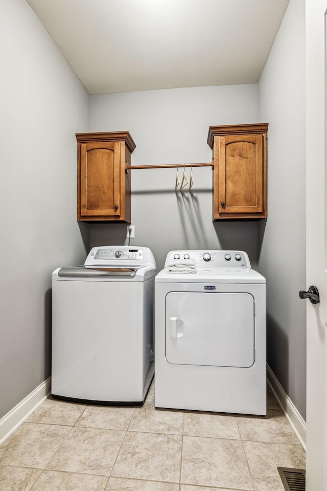 washroom with washing machine and clothes dryer, light tile patterned flooring, and cabinets