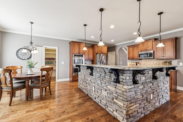 kitchen featuring a kitchen bar, stainless steel appliances, tasteful backsplash, and hanging light fixtures