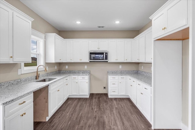 kitchen with light stone counters, sink, white cabinets, and dark hardwood / wood-style floors