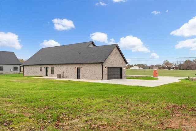 back of property with a garage, central AC unit, and a lawn