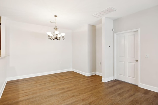 unfurnished room with hardwood / wood-style floors and an inviting chandelier