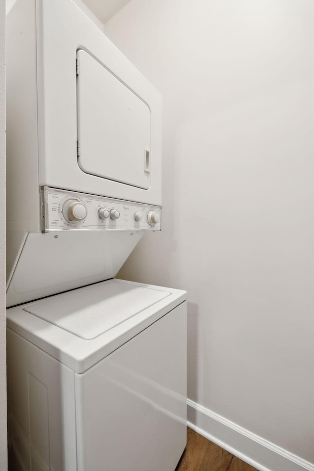 laundry area with dark hardwood / wood-style flooring and stacked washer / dryer