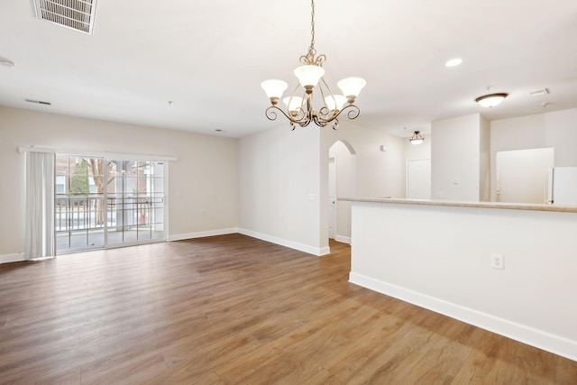 spare room with wood-type flooring and an inviting chandelier