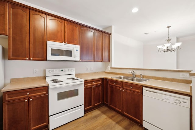 kitchen with white appliances, sink, decorative light fixtures, a notable chandelier, and light hardwood / wood-style floors