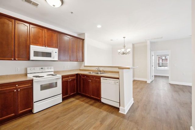 kitchen featuring white appliances, sink, decorative light fixtures, a chandelier, and light hardwood / wood-style floors