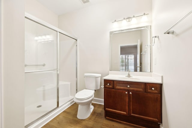 bathroom with a shower with door, vanity, wood-type flooring, and toilet