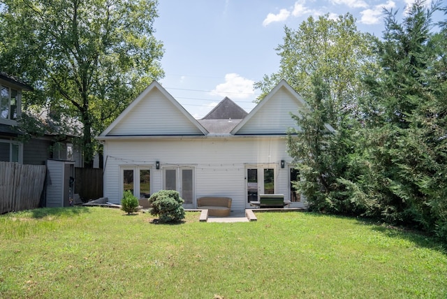 rear view of house featuring a lawn, french doors, and a patio