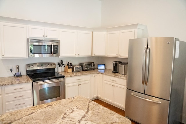 kitchen featuring light stone countertops, white cabinetry, dark wood-type flooring, and appliances with stainless steel finishes